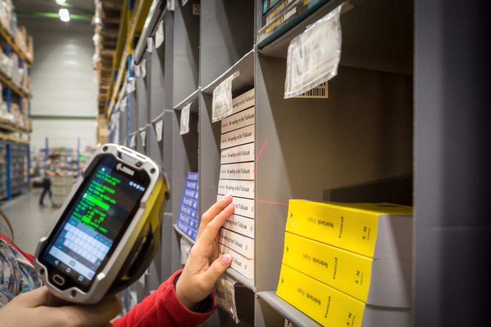 A&#x20;person&#x20;holding&#x20;a&#x20;scanner&#x20;while&#x20;picking&#x20;books&#x20;in&#x20;a&#x20;Storeganizer&#x20;installation