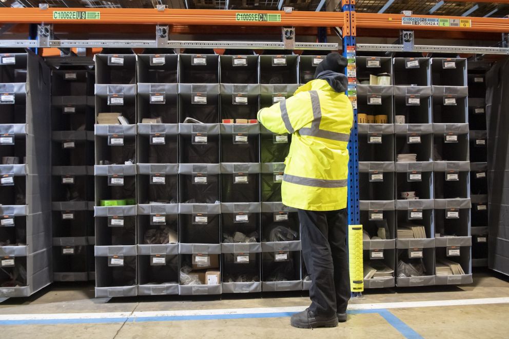 A&#x20;person&#x20;in&#x20;a&#x20;yellow&#x20;coat&#x20;that&#x20;is&#x20;picking&#x20;orders&#x20;in&#x20;a&#x20;Storeganizer&#x20;rack